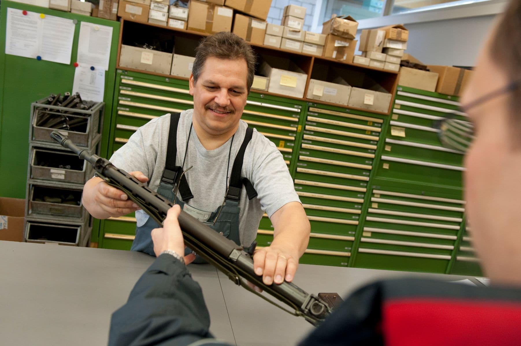 Wurde bei mir noch in Uniform über die Schweizerfahne vom Kadi übergeben: Die persönliche Waffe. Hier ists ein LBA-Mitarbeiter, der einem Rekruten, noch in Zivil, die Waffe übergibt.